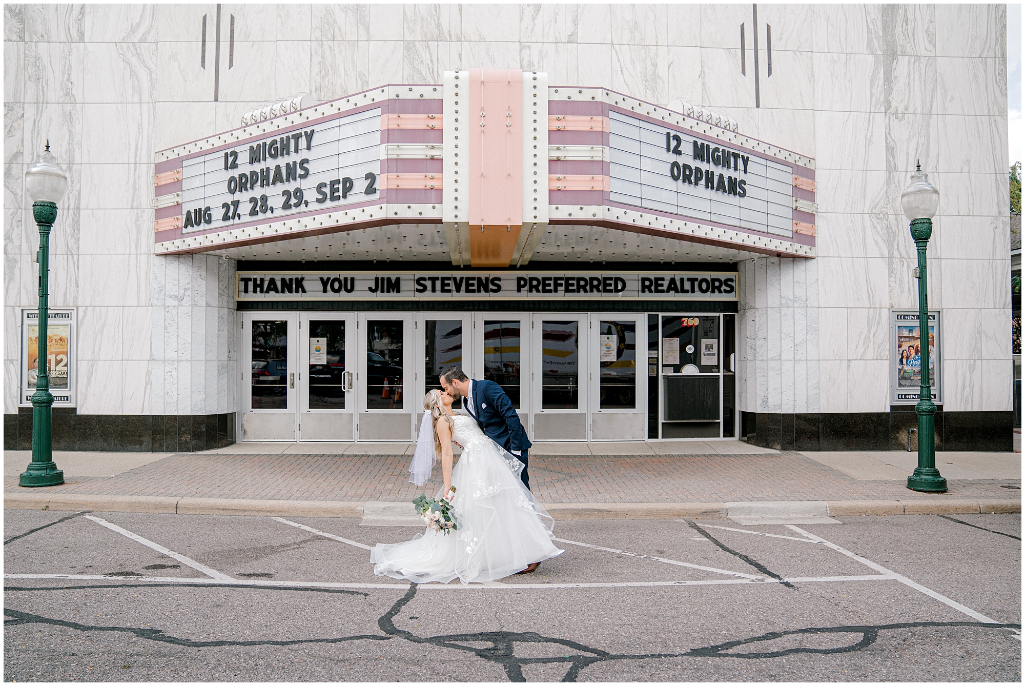 bride and groom kiss outside movie theatre
