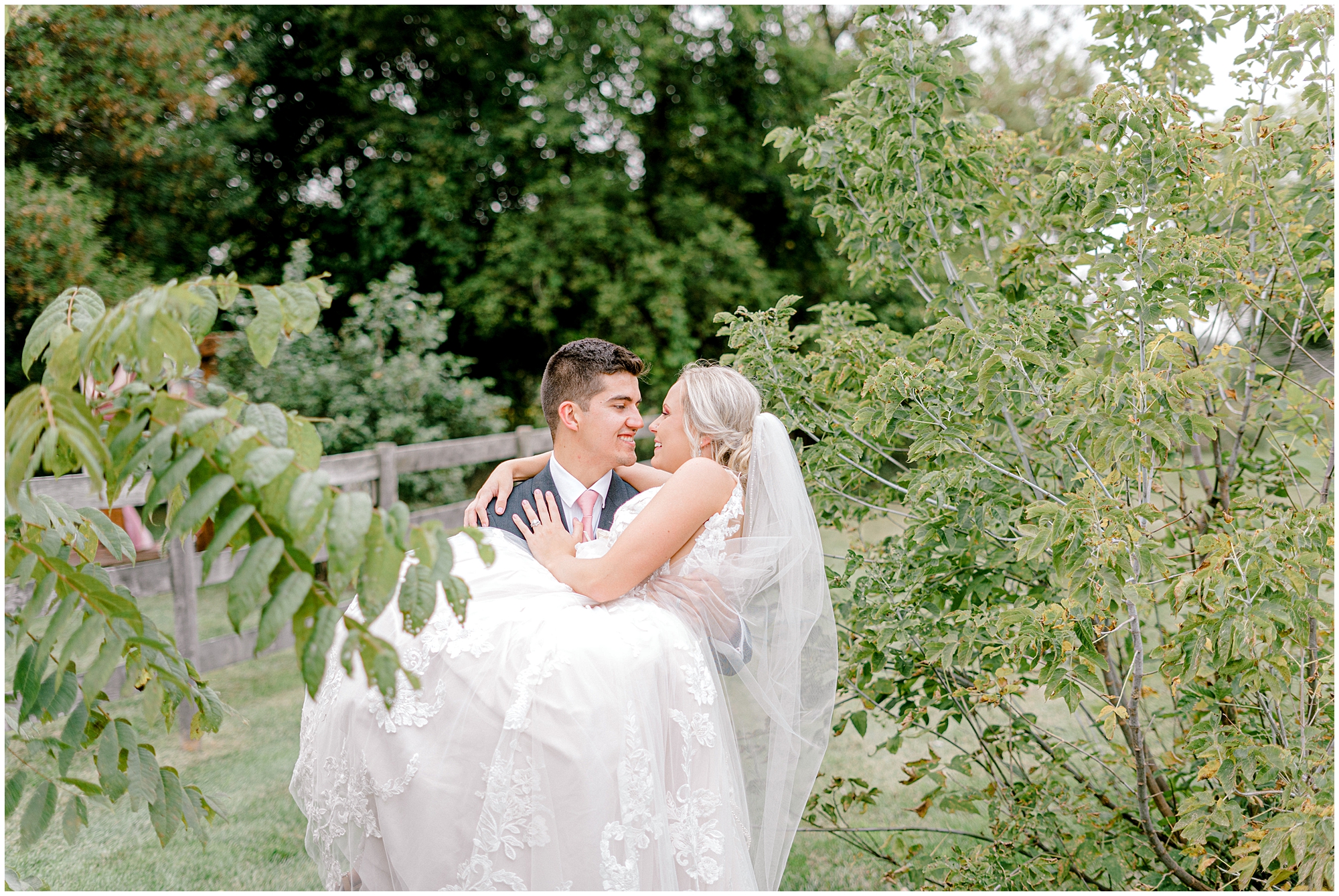 groom carries bride during outdoor wedding photos