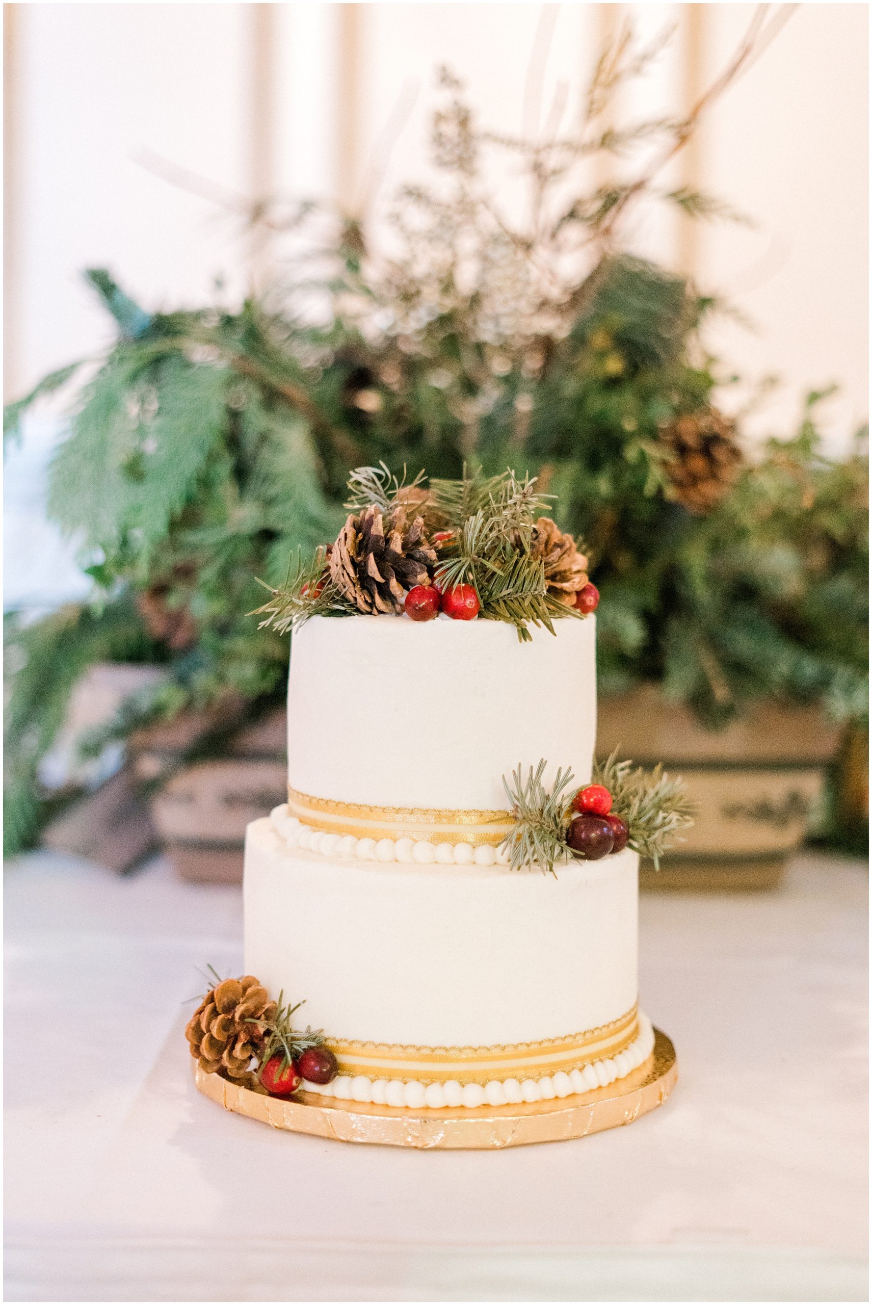 white and gold wedding cake with pinecone cake topper