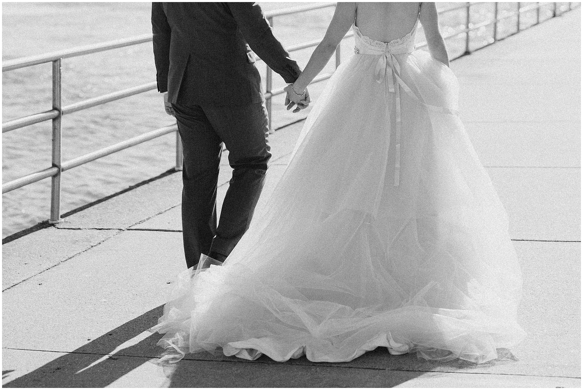 black and white photo of bride and groom walking by the water